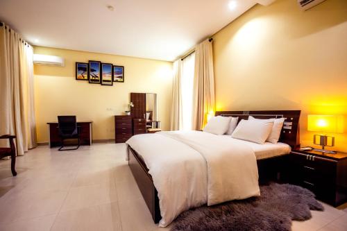 a bedroom with a large white bed and a desk at Rushmore - Luxury Suite in Lagos