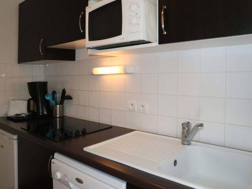 une cuisine avec un évier et un micro-ondes dans l'établissement Appartement Confort 4 pers. aux Orres 1800 avec Piscine, Sauna, Hammam et Wifi Gratuit - FR-1-322-89, aux Orres
