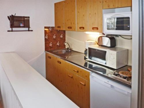 une petite cuisine avec un micro-ondes et une cuisinière dans l'établissement Studio cosy Les Orres, 300m commerces, 150m remontée, parking, animaux admis - FR-1-322-271, aux Orres