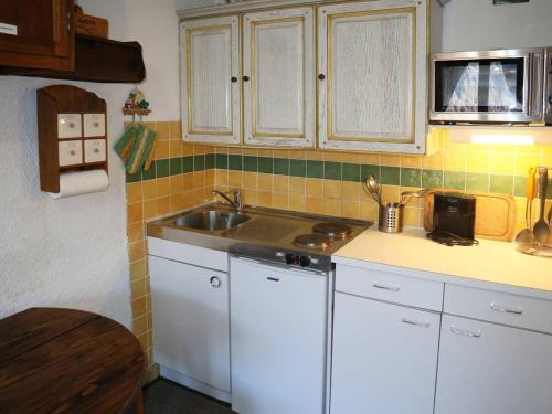 une cuisine avec des armoires blanches et un évier dans l'établissement Studio skis aux pieds, 4 pers, balcon sud - FR-1-322-107, aux Orres