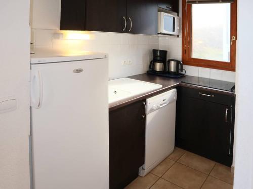 une cuisine avec un réfrigérateur blanc et un évier dans l'établissement Chalet d'exception avec piscine, sauna et hammam, au pied des pistes des Orres - FR-1-322-124, aux Orres