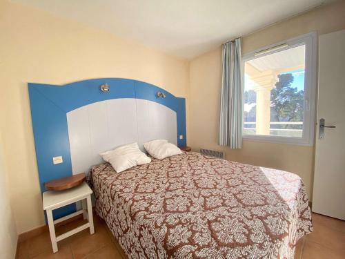 - une chambre avec un lit doté d'une tête de lit bleue et d'une fenêtre dans l'établissement Appartement T2 avec Piscine à 300m de la Plage – 3 Couchages, Parking et Balcon Meublé - FR-1-245-34, à La Baule