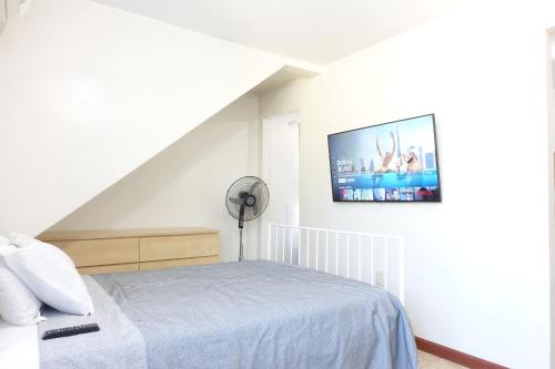 1 dormitorio con 1 cama y TV en la pared en 1 Bus Stop To NYC-Hot Tub-EWR Airport-Free Parking, en Hillside