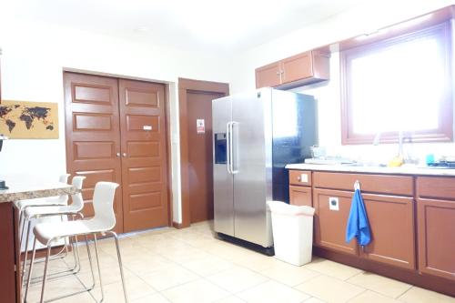 a kitchen with a stainless steel refrigerator and wooden cabinets at 1 Bus Stop To NYC-Hot Tub-EWR Airport-Free Parking in Hillside