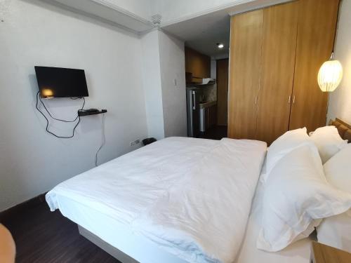 a bedroom with a white bed with a tv on the wall at Accommodation Service in Manila