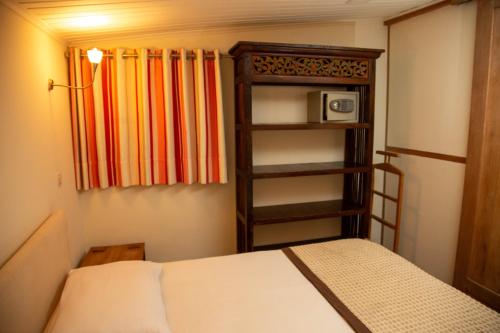 a bedroom with a bed and a book shelf with a microwave at Hotel La Villette in Antananarivo