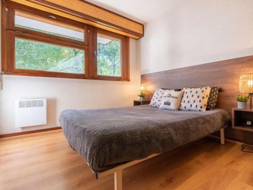 a bedroom with a large bed with two windows at Appartement Saint-Lary-Soulan, 2 pièces, 4 personnes - FR-1-296-198 in Saint-Lary-Soulan