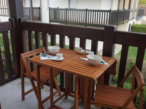- une table en bois avec 2 bols et 2 chaises sur une terrasse couverte dans l'établissement Appartement cosy 4 pers à 300m de la plage de Cabourg avec tout confort - FR-1-465-21, à Cabourg