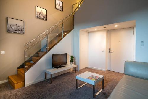 a living room with a staircase and a tv at INNSiDE by Meliá Dresden in Dresden