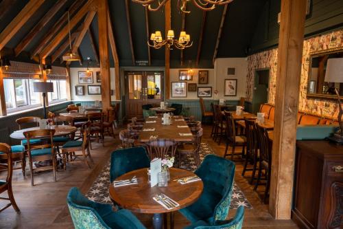 een eetkamer met tafels en stoelen en een kroonluchter bij Ely Hotel by Chef & Brewer Collection in Camberley