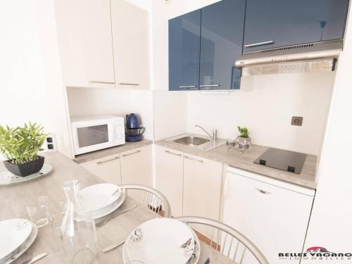 une cuisine avec des armoires blanches et une table avec des chaises dans l'établissement Charmant Studio Cabine 4 Pers. avec Balcon, proche Centre et Thermes à Saint-Lary-Soulan - FR-1-296-231, à Saint-Lary-Soulan