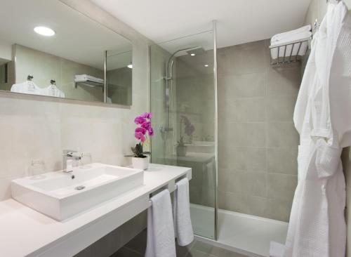 een witte badkamer met een wastafel en een douche bij Insotel Cala Mandia Resort in Cala Mendia