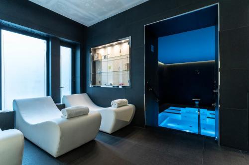 a living room with two white chairs and a mirror at LHP Hotel Montecatini Palace & SPA in Montecatini Terme