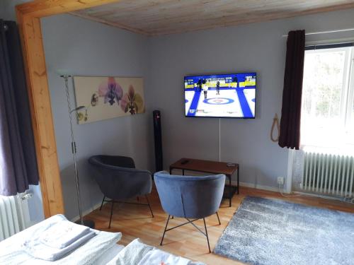 a room with two chairs and a tv on the wall at Geijersholms Herrgård in Hagfors