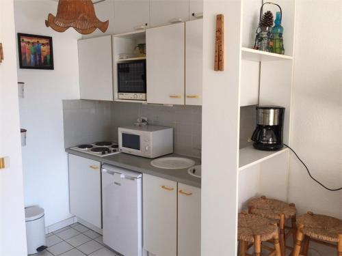 une petite cuisine avec des armoires blanches et un micro-ondes dans l'établissement Studio cabine 4 pers près de la plage avec parking à Argelès-sur-Mer - FR-1-388-17, à Argelès-sur-Mer