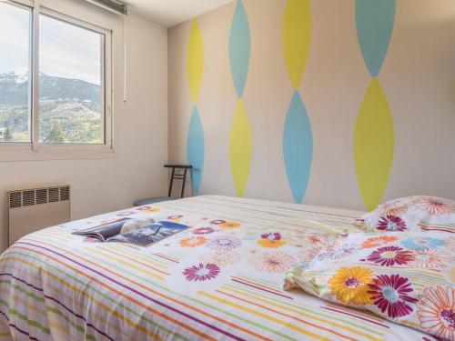 Un dormitorio con una cama con un edredón colorido. en Appart 2 pièces avec balcon, près des pistes - Briançon - FR-1-330C-20, en Briançon