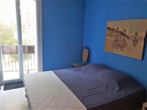 une chambre bleue avec un lit et une fenêtre dans l'établissement Appartement T2 à 50m de la plage avec balcon et parking – Argelès-sur-Mer - FR-1-388-43, à Argelès-sur-Mer
