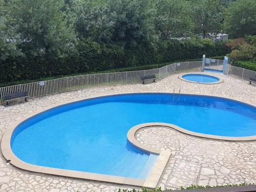 une grande piscine bleue entourée d'une clôture. dans l'établissement Appartement lumineux T2 avec piscine, loggia et parking, 4 couchages - Argelès-sur-Mer - FR-1-388-55, à Argelès-sur-Mer