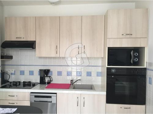La cuisine est équipée de placards en bois, d'un évier et d'un four micro-ondes. dans l'établissement Maison 5 pers. à La Tranche sur Mer, Proche Plage, Terrasse, Garage, Dordonnée - FR-1-357-109, à La Tranche-sur-Mer