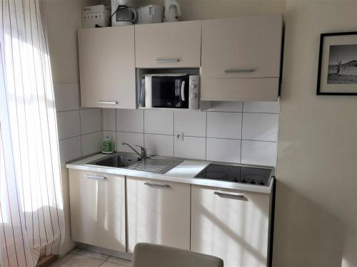 une petite cuisine avec un évier et un micro-ondes dans l'établissement Appartement rénové 3 pièces, proche gare et remontées mécaniques - FR-1-330C-84, à Briançon