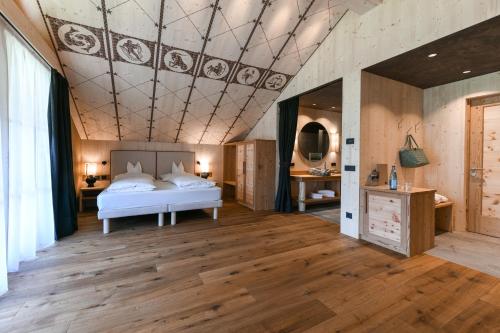 1 dormitorio con cama y techo artesonado en Dolomites Living Hotel Tirler, en Alpe di Siusi