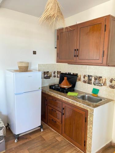 uma cozinha com um frigorífico branco e um lavatório em Imsouanegreenwave em Imsouane