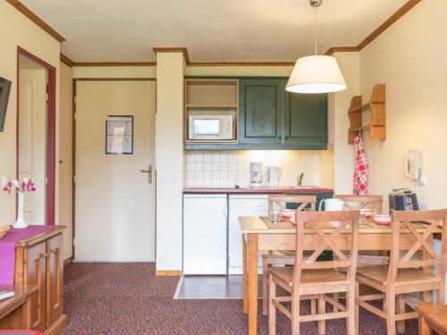 une cuisine avec des placards verts et une table et des chaises en bois dans l'établissement Charmant 2 pièces au cœur de La Salle-les-Alpes, proche télécabines et commerces, 4 couchages - FR-1-330F-45, à Serre Chevalier