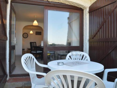 - une table et des chaises blanches sur une terrasse couverte dans l'établissement Appartement rénové 4 pers avec terrasse et WIFI - Banyuls - FR-1-225C-34, à Banyuls-sur-Mer