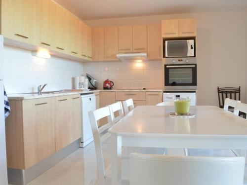 - une cuisine avec une table et une table et des chaises blanches dans l'établissement Appartement moderne 2 chambres avec terrasse, parking et climatisation à Banyuls-sur-Mer - FR-1-225C-531, à Banyuls-sur-Mer