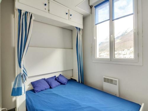 une chambre avec un lit avec des oreillers bleus et une fenêtre dans l'établissement Appartement cosy pour 4 personnes avec ascenseur, à 350m des pistes au centre de Cauterets - FR-1-401-25, à Cauterets
