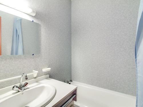 une salle de bain blanche avec un lavabo et un miroir dans l'établissement Appartement cosy pour 4 personnes avec ascenseur, à 350m des pistes au centre de Cauterets - FR-1-401-25, à Cauterets