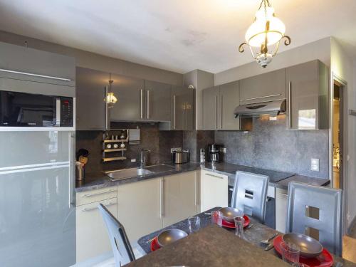 une cuisine avec des armoires blanches et une table avec des chaises dans l'établissement Cauterets: Apt 2 Chambres, Balcon, WIFI - FR-1-401-26, à Cauterets