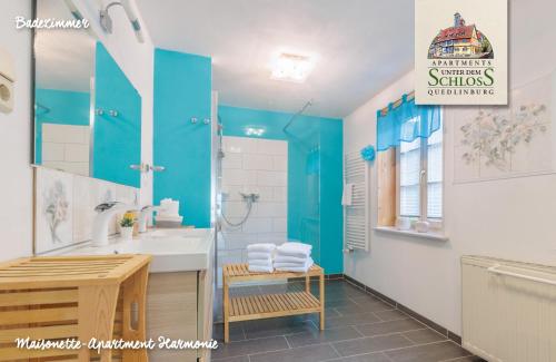 La salle de bains est pourvue de murs bleus, d'un lavabo et d'un miroir. dans l'établissement Apartments Unter Dem Schloß, à Quedlinbourg