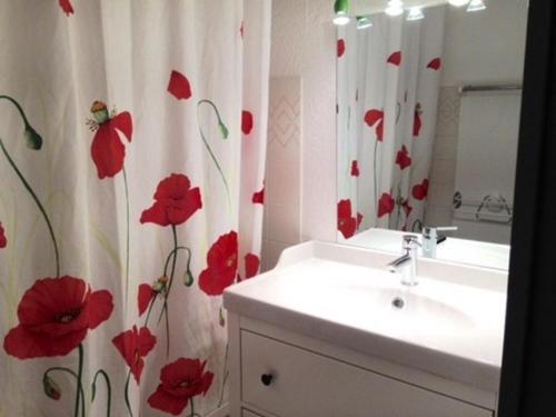 een badkamer met een wastafel en een douchegordijn met rode bloemen bij Studio La Mongie, 2 pièces, 6 personnes - FR-1-404-111 in La Mongie