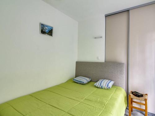 une chambre avec un lit vert avec deux oreillers dans l'établissement Appartement rénové pour 4 pers, 1 chambre, parking, centre de Cauterets, proche télécabine - FR-1-401-84, à Cauterets