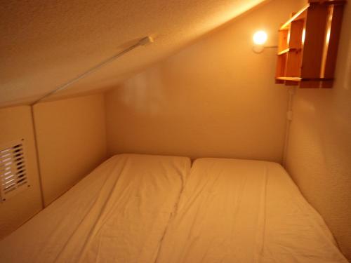 a small bed in a small room with a light at Studio Peisey-Vallandry, 1 pièce, 4 personnes - FR-1-411-75 in Landry