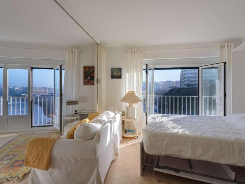 une chambre blanche avec un lit et un balcon dans l'établissement Studio cosy à Biarritz avec vue sur l'océan, 2e étage, ascenseur - FR-1-3-483, à Biarritz
