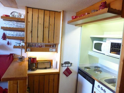 une petite cuisine avec une cuisinière et un micro-ondes dans l'établissement Charmant duplex classé 3 cristaux, 6 pers, proche pistes, balcons Nord-Sud, Arc 1800 - FR-1-411-179, à Arc 1800