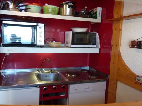 une petite cuisine avec un évier et un micro-ondes dans l'établissement Appartement Duplex 52m², 7 pers, proche pistes/commerces, animaux admis, parking, Wi-Fi - FR-1-411-195, à Arc 1800