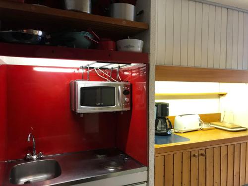 Il comprend une cuisine dotée d'un mur rouge et d'un four micro-ondes. dans l'établissement Studio 4 personnes Arc 1600 à 50m des pistes, balcon, TV - FR-1-411-335, à Arc 1600