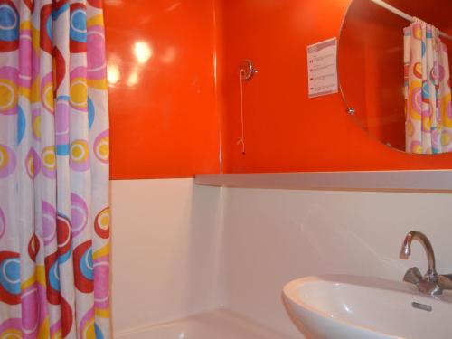La salle de bains orange est pourvue d'un lavabo et d'un miroir. dans l'établissement ### Titre proposé : Studio 5 pers, skis aux pieds, proche commerces et pistes, Charvet Arc 1800 - FR-1-411-470, à Arc 1800