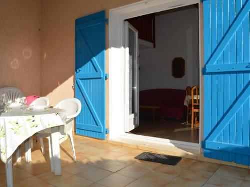une chambre avec une porte bleue et une table avec une table blanche dans l'établissement Maison cosy avec mezzanine, terrasse, piscine et parking – Saint-Cyprien - FR-1-225D-558, à Saint Cyprien Plage