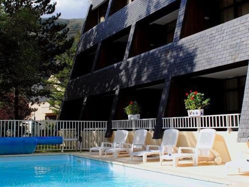 un groupe de chaises assises à côté d'une piscine dans l'établissement Studio rénové pour 4 pers. avec piscine, sauna et balcon à Saint-Lary-Soulan - FR-1-296-257, à Saint-Lary-Soulan