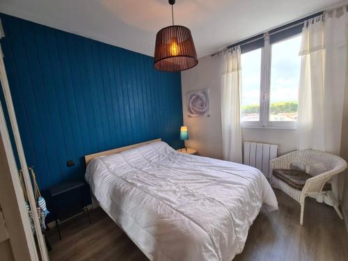 une chambre avec un lit et un mur bleu dans l'établissement Appartement moderne 3 pièces, 6 couchages, parking, proche plage - FR-1-224C-648, à Saint-Jean-de-Monts