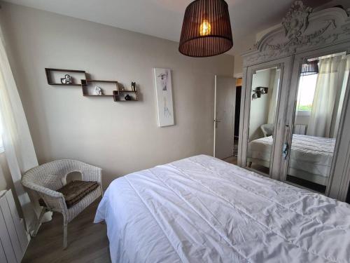 une chambre avec un lit blanc et une chaise dans l'établissement Appartement moderne 3 pièces, 6 couchages, parking, proche plage - FR-1-224C-648, à Saint-Jean-de-Monts