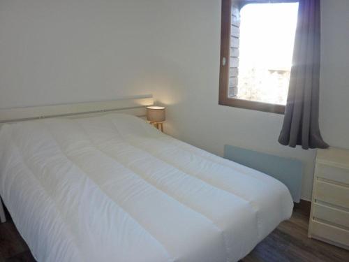 uma cama branca num quarto com uma janela em Appartement Les Orres, 2 pièces, 6 personnes - FR-1-322-311 em Les Orres