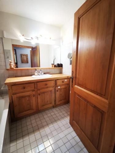 La salle de bains est pourvue d'un lavabo et d'une porte en bois. dans l'établissement MAGNIFIQUE Appart/ 8 pers / 4 ch / Jardin / Vue MB, à Megève
