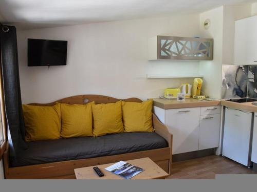 - un salon avec un canapé et des oreillers jaunes dans l'établissement Studio Cabine à Montgenèvre - Face aux Pistes, Wifi, Animaux Acceptés - FR-1-266-131, à Montgenèvre