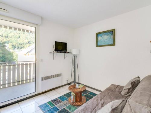 un salon avec un canapé, une télévision et une fenêtre dans l'établissement Studio cabine avec parking proche centre Luz-Saint-Sauveur, balcon, pour 4 pers. - FR-1-402-66, à Luz-Saint-Sauveur