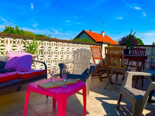 een patio met stoelen en een tafel met wijnglazen erop bij l appart de Lilly in Pierry